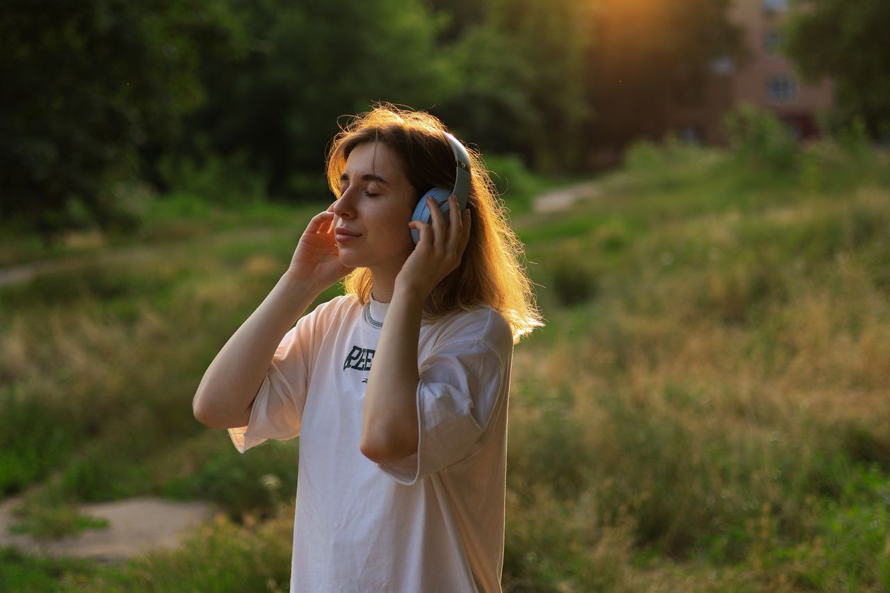 A woman listening to music through headphones outdoors